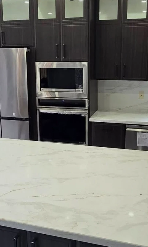 A dark cabinets with white and gray countertop kitchen renovation project completed by Titan Cabinetry